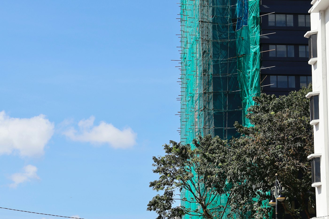 Scaffolding wrapped in green netting on a building site